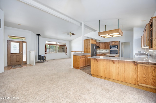 5375 Vinewood Cir, Fallon, NV 89406 - kitchen with stainless steel appliances, a wood stove, carpet floors, and a peninsula