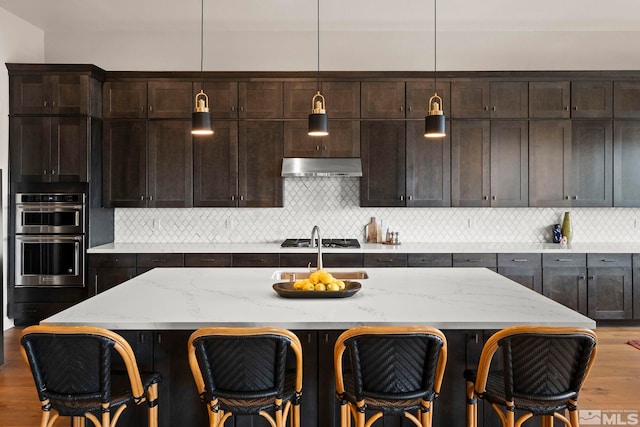 3019 Copper Stone Dr, Reno, NV 89521 - kitchen featuring double oven, a sink, wood finished floors, under cabinet range hood, and pendant lighting