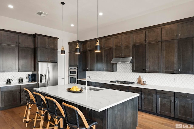 3019 Copper Stone Dr, Reno, NV 89521 - kitchen with a sink, under cabinet range hood, stainless steel appliances, backsplash, and light wood-style floors