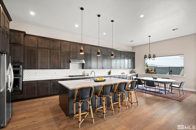 3019 Copper Stone Dr, Reno, NV 89521 - kitchen featuring appliances with stainless steel finishes, decorative backsplash, light countertops, a breakfast bar area, and recessed lighting