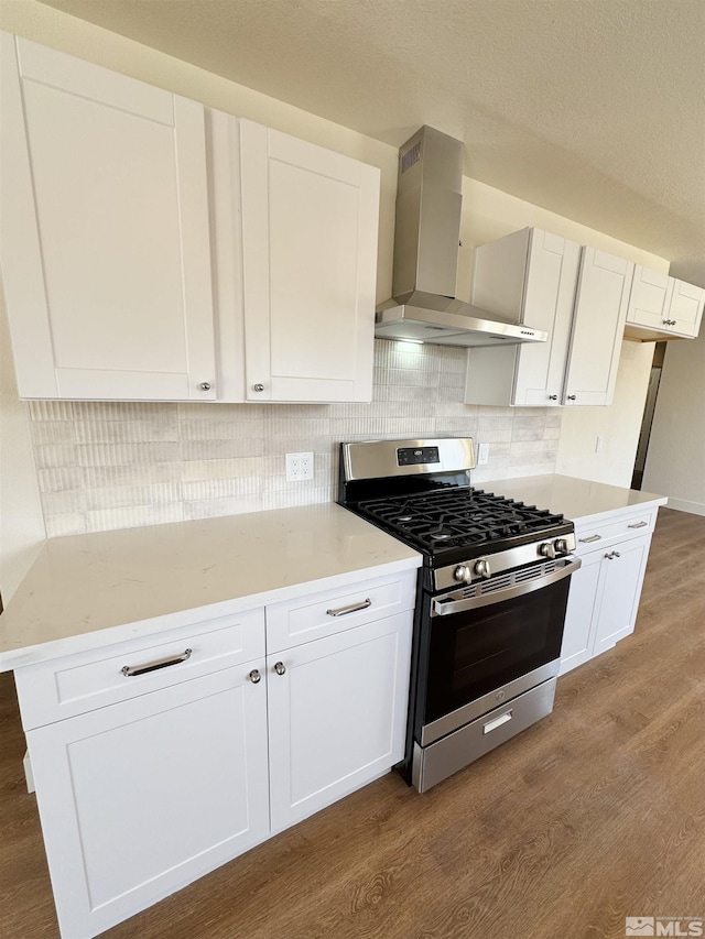 3003 Alcorn Rd, Fallon, NV 89406 - kitchen featuring gas range, wall chimney exhaust hood, dark wood-type flooring, and white cabinetry