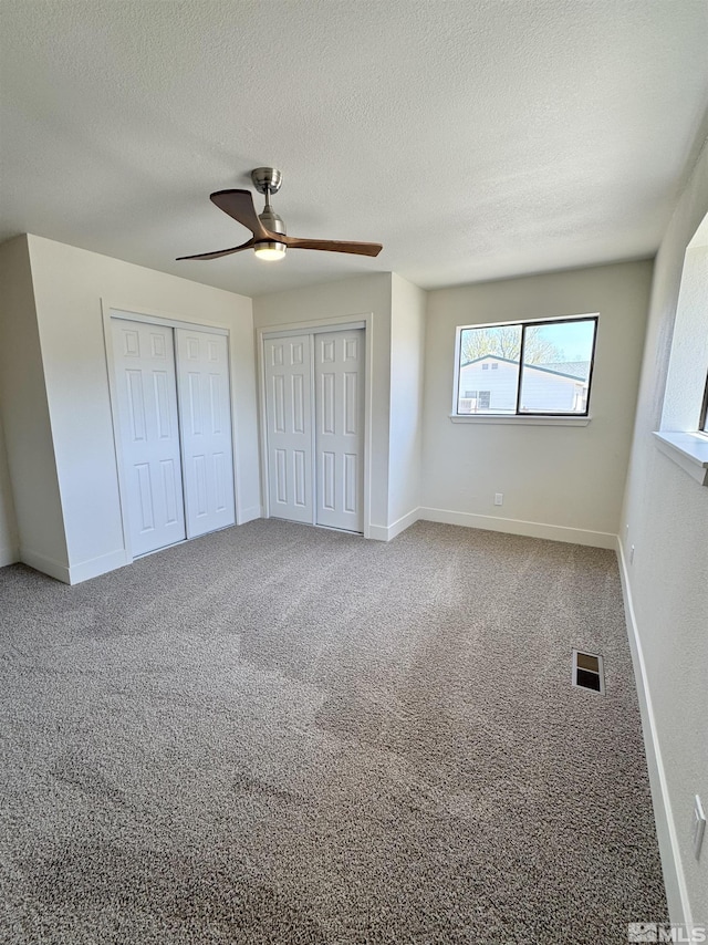 3003 Alcorn Rd, Fallon, NV 89406 - unfurnished bedroom with a textured ceiling, two closets, carpet floors, ceiling fan, and baseboards