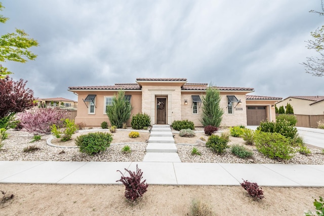 13335 Satinspar Dr, Reno, NV 89511 - mediterranean / spanish house featuring an attached garage, stone siding, a tiled roof, stucco siding, and fence