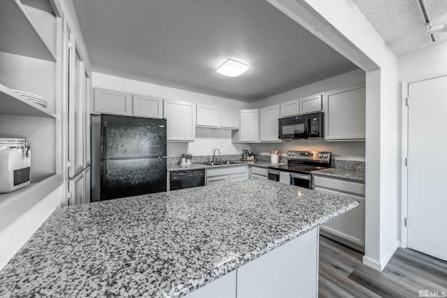 1465 E Peckham Ln Apt 20, Reno, NV 89502 - kitchen with black appliances, light stone counters, dark wood-type flooring, a sink, and a textured ceiling