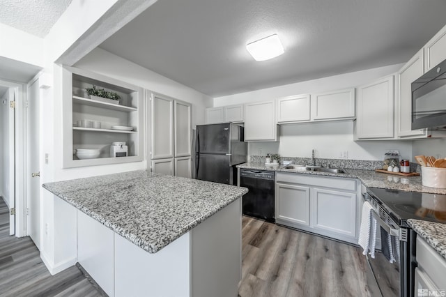 1465 E Peckham Ln Apt 20, Reno, NV 89502 - kitchen featuring a sink, black appliances, wood finished floors, light stone counters, and a textured ceiling