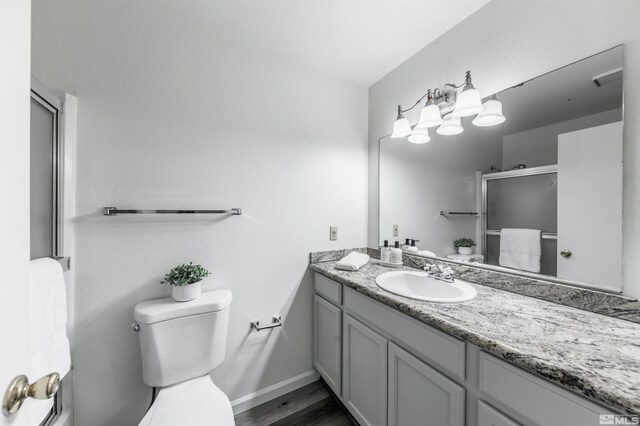1465 E Peckham Ln Apt 20, Reno, NV 89502 - bathroom featuring toilet, a shower with door, vanity, baseboards, and wood finished floors