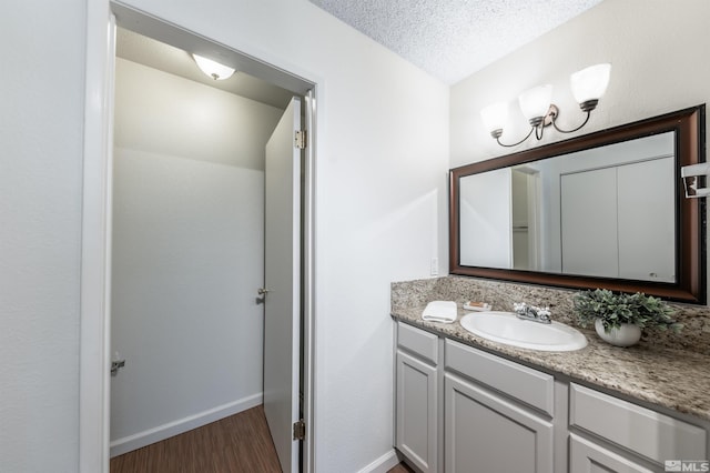 1465 E Peckham Ln Apt 20, Reno, NV 89502 - bathroom with wood finished floors, vanity, baseboards, a textured ceiling, and a chandelier
