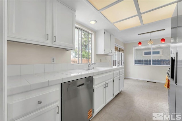 1280 O Callaghan Dr, Sparks, NV 89434 - kitchen with stainless steel dishwasher, white cabinets, tile counters, hanging light fixtures, and baseboards