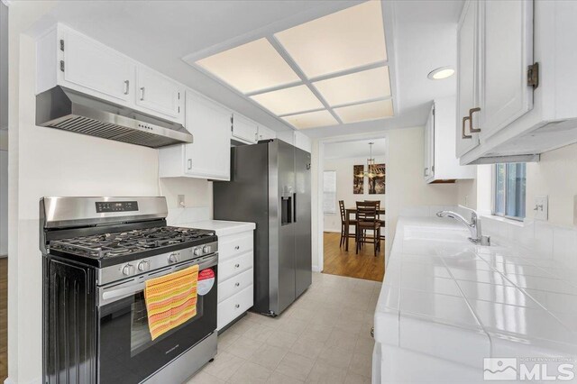 1280 O Callaghan Dr, Sparks, NV 89434 - kitchen featuring stainless steel appliances, under cabinet range hood, tile countertops, a sink, and white cabinetry