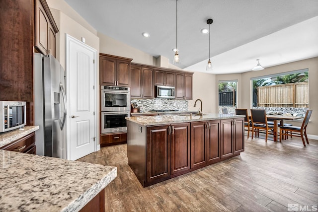 16885 Majestic View Dr, Reno, NV 89521 - kitchen with appliances with stainless steel finishes, a sink, decorative backsplash, dark wood finished floors, and a center island with sink