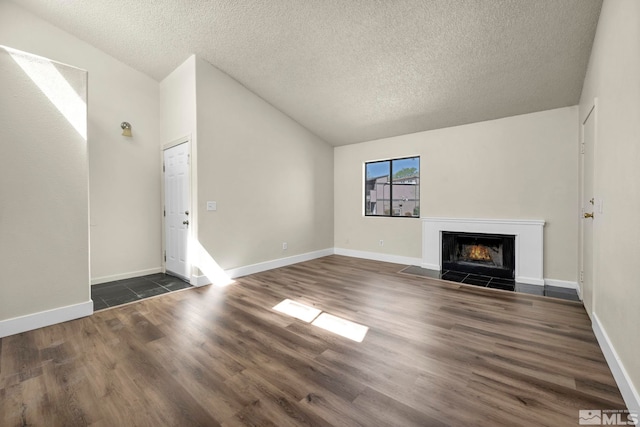 2375 Tripp Dr Unit 2, Reno, NV 89512 - unfurnished living room with dark wood-style floors, a fireplace with flush hearth, vaulted ceiling, a textured ceiling, and baseboards