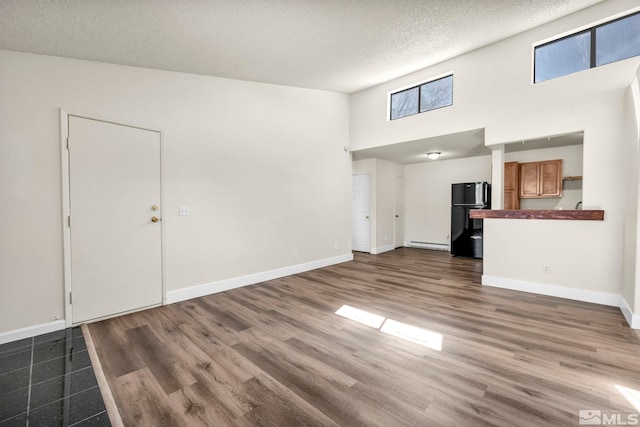 2375 Tripp Dr Unit 2, Reno, NV 89512 - unfurnished living room with a baseboard radiator, a towering ceiling, baseboards, a textured ceiling, and wood finished floors