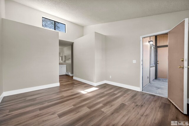 2375 Tripp Dr Unit 2, Reno, NV 89512 - empty room with wood finished floors, a textured ceiling, baseboards, and a towering ceiling