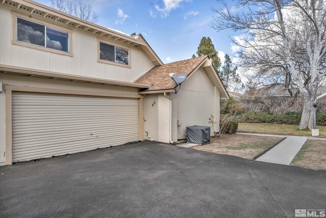 40 Condor Cir, Carson City, NV 89701 - view of side of home featuring central AC unit, a shingled roof, and asphalt driveway