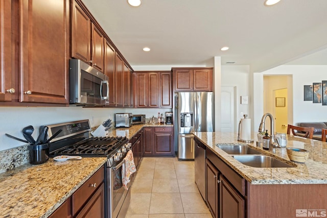 1845 Fledge Creek Dr, Reno, NV 89521 - kitchen featuring stainless steel appliances, a sink, a kitchen island with sink, light tile patterned floors, and light stone countertops