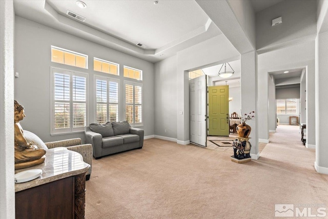 living area with light carpet, baseboards, and a high ceiling