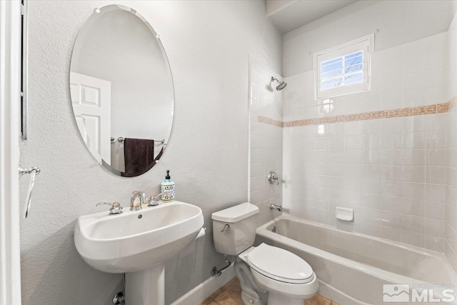 bathroom with toilet,  shower combination, a sink, and baseboards