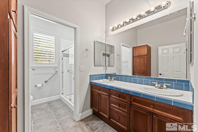full bath featuring a stall shower, double vanity, baseboards, and toilet