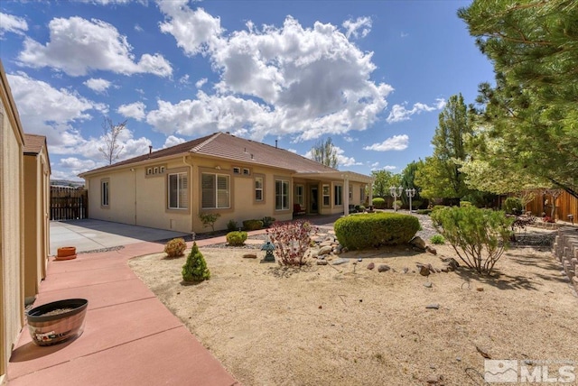 rear view of property featuring a patio area, fence, and stucco siding