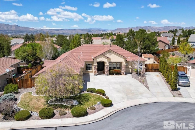 view of front of property with a tiled roof, a mountain view, fence, stone siding, and stucco siding