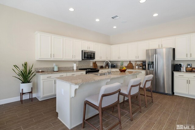 3335 Show Jumper, Reno, NV 89521 - kitchen with appliances with stainless steel finishes, dark wood-type flooring, recessed lighting, white cabinets, and a center island with sink