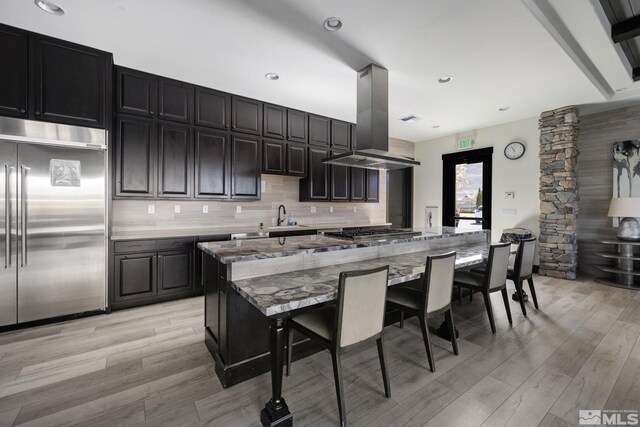 3335 Show Jumper, Reno, NV 89521 - kitchen with stainless steel appliances, island exhaust hood, light wood-style flooring, a breakfast bar area, and tasteful backsplash