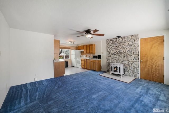 9499 Wigwam Way, Reno, NV 89506 - unfurnished living room featuring a wood stove, ceiling fan, and light carpet