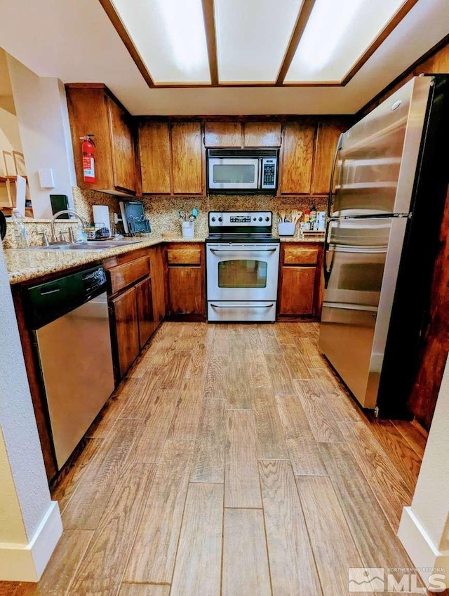 416 Quaking Aspen Ln Unit P, Stateline, NV 89449 - kitchen featuring stainless steel appliances, a sink, brown cabinetry, light wood-type flooring, and backsplash
