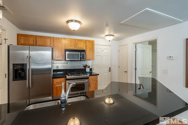 1450 Idlewild Dr Unit 1121, Reno, NV 89509 - kitchen with stainless steel appliances, dark countertops, decorative backsplash, brown cabinetry, and a sink