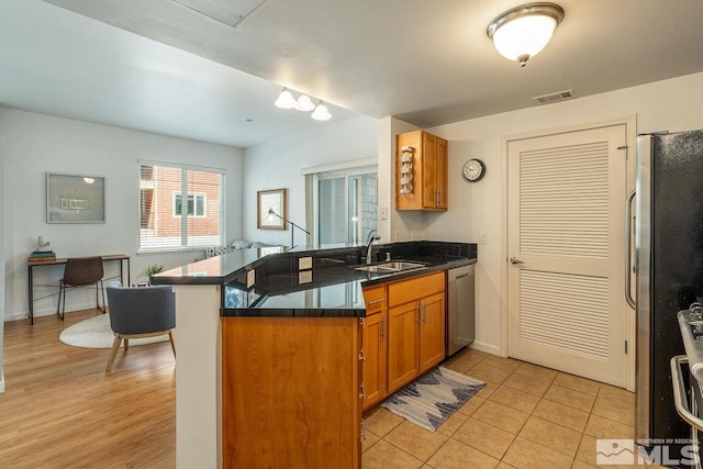 1450 Idlewild Dr Unit 1121, Reno, NV 89509 - kitchen featuring a sink, appliances with stainless steel finishes, a peninsula, brown cabinetry, and baseboards