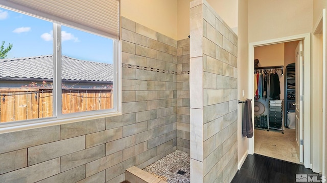 2485 Firenze Dr, Sparks, NV 89434 - bathroom featuring tiled shower, a spacious closet, and wood finished floors