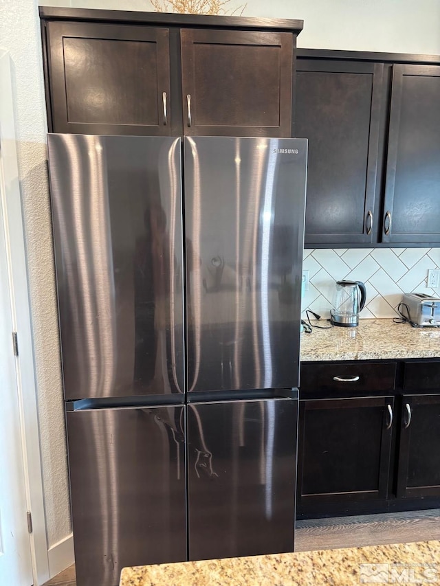 2269 Millville Dr, Sparks, NV 89441 - kitchen with freestanding refrigerator, decorative backsplash, light stone countertops, and dark brown cabinets