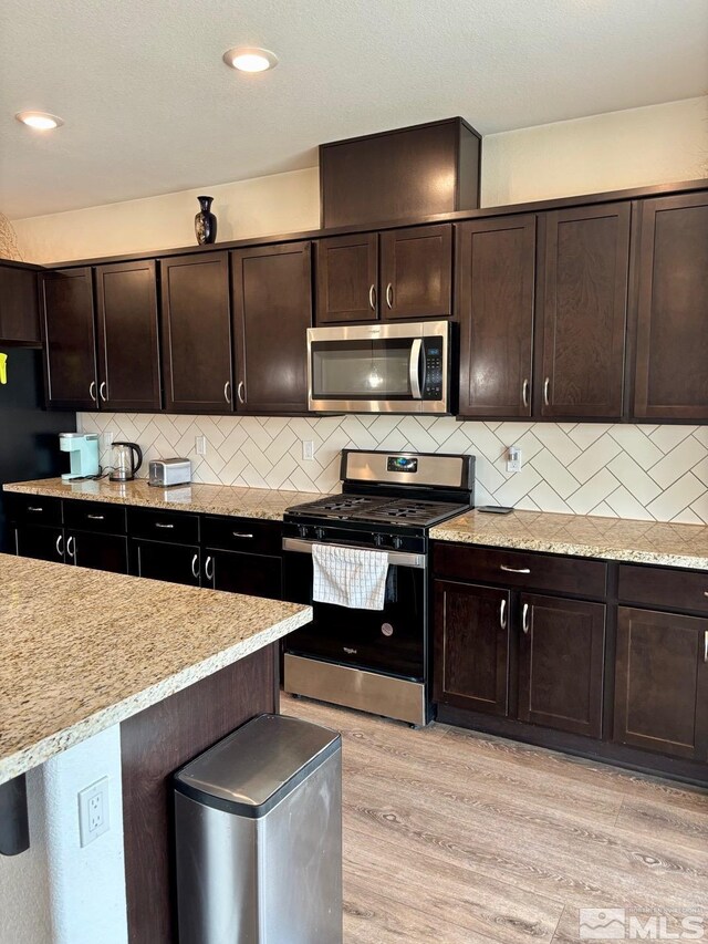 2269 Millville Dr, Sparks, NV 89441 - kitchen featuring appliances with stainless steel finishes, light wood-style floors, dark brown cabinetry, and decorative backsplash