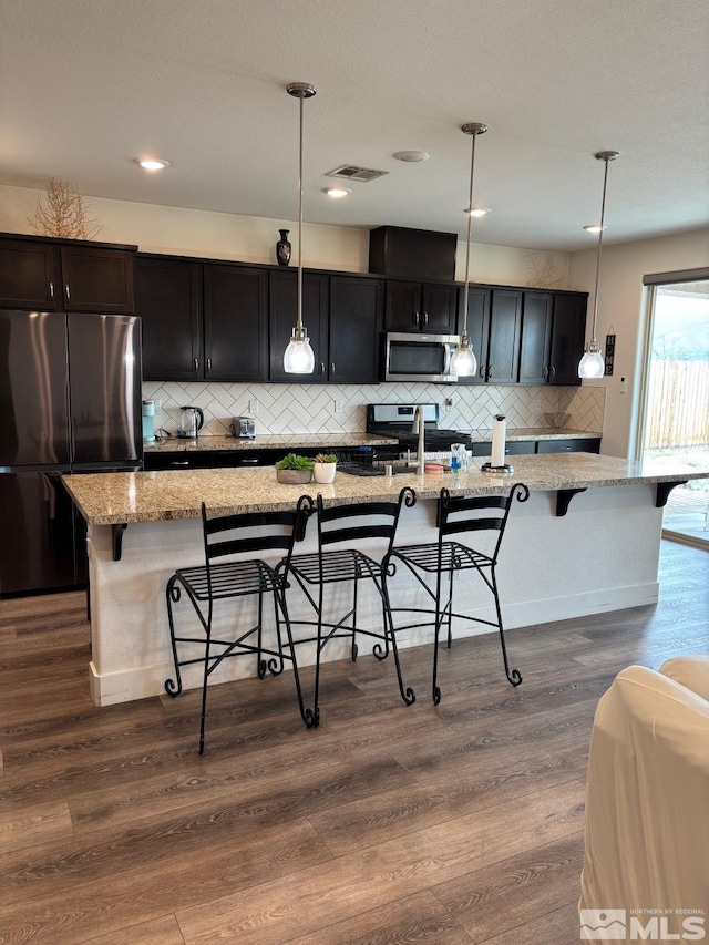 2269 Millville Dr, Sparks, NV 89441 - kitchen with stainless steel appliances, a kitchen bar, decorative backsplash, a large island, and light stone countertops
