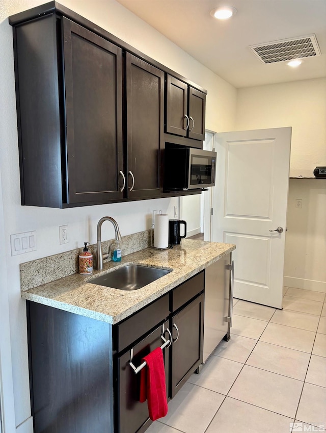 2269 Millville Dr, Sparks, NV 89441 - kitchen with a sink, stainless steel microwave, light tile patterned floors, recessed lighting, and dark brown cabinetry