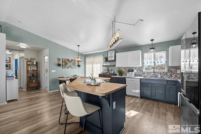 2036 Flycatcher Ct, Sparks, NV 89441 - kitchen featuring dishwasher, lofted ceiling, light wood-style flooring, a center island, and backsplash