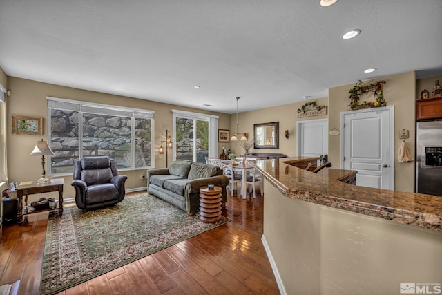 living room with dark wood-style flooring, recessed lighting, a textured ceiling, and baseboards
