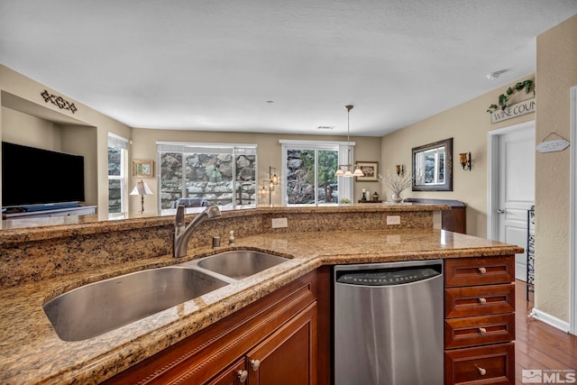 kitchen with dishwasher, a sink, dark wood-style flooring, light stone counters, and healthy amount of natural light