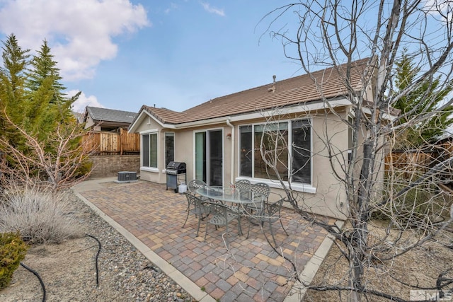 rear view of house featuring stucco siding, a patio area, fence, a tile roof, and central AC unit