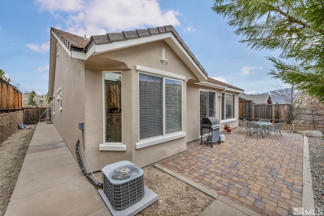 rear view of house featuring stucco siding, a patio, central air condition unit, a fenced backyard, and outdoor dining area