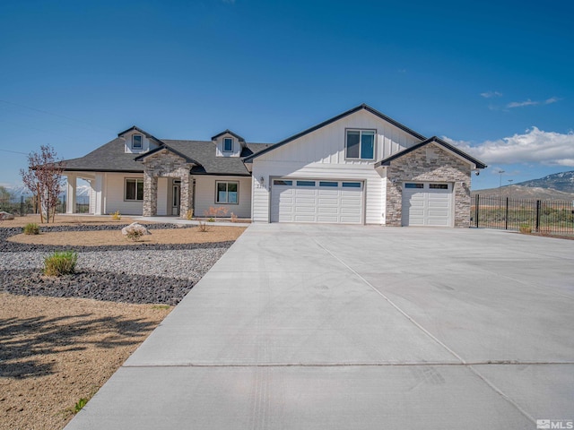5376 S Edmonds Dr, Carson City, NV 89701 - view of front facade with stone siding, fence, concrete driveway, a garage, and covered porch