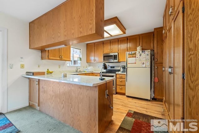 248 Woodlake Cir, Dayton, NV 89403 - kitchen featuring stainless steel appliances, a peninsula, light countertops, brown cabinets, and a sink