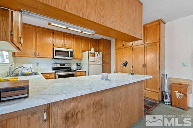248 Woodlake Cir, Dayton, NV 89403 - kitchen featuring appliances with stainless steel finishes, a sink, a peninsula, brown cabinets, and light carpet