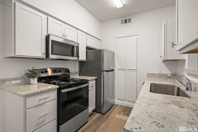 6850 Sharlands Ave Unit Y1149, Reno, NV 89523 - kitchen featuring stainless steel appliances, a sink, light wood-style floors, white cabinets, and light stone counters