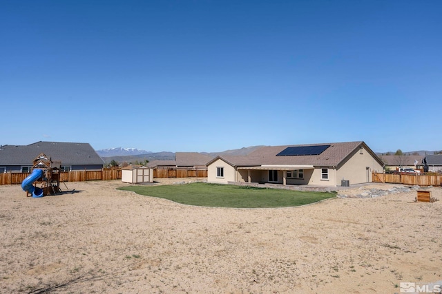 7760 Sonic Ct, Sparks, NV 89436 - rear view of property featuring a shed, roof mounted solar panels, an outbuilding, a playground, and stucco siding