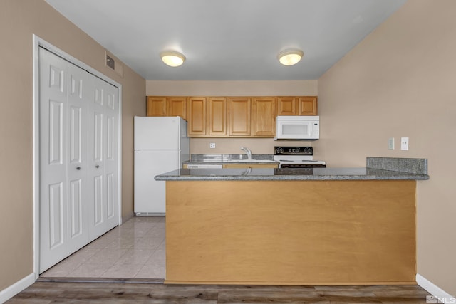 3089 Cashill Blvd, Reno, NV 89509 - kitchen with white appliances, a sink, a peninsula, baseboards, and dark stone counters