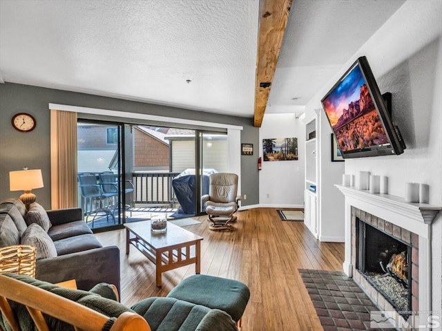 555 Tahoe Keys Blvd Unit 14, South Lake Tahoe, CA 96150 - living room featuring beam ceiling, hardwood / wood-style floors, a tile fireplace, baseboards, and a textured ceiling