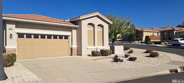 1360 Veneto Dr, Sparks, NV 89434 - mediterranean / spanish-style house featuring an attached garage, driveway, a tile roof, stucco siding, and stone siding