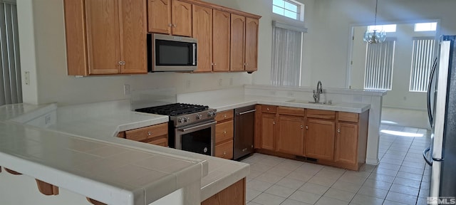 1360 Veneto Dr, Sparks, NV 89434 - kitchen featuring stainless steel appliances, a peninsula, a sink, light tile patterned floors, and a chandelier