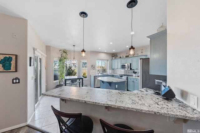 2900 Ariel Dr, Reno, NV 89523 - kitchen with stainless steel appliances, a peninsula, blue cabinets, and a kitchen breakfast bar